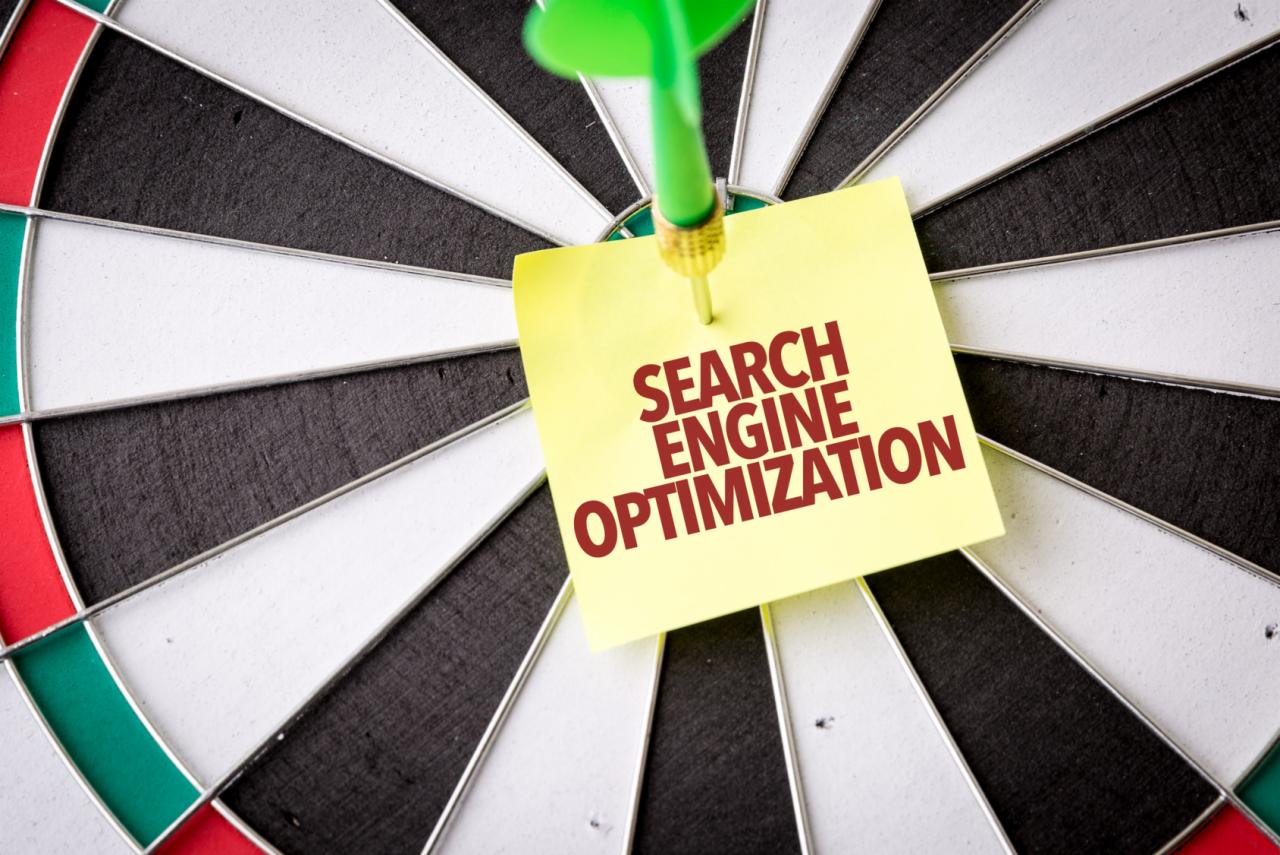 Strzałka z żółtą karteczką z napisem 'SEARCH ENGINE OPTIMIZATION' wbita w tarczę do darta.
