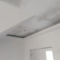 Niedokończony sufit podwieszany z płyt kartonowo-gipsowych z widocznym otworem na oświetlenie, szpachlowany, w surowym stanie, ściany również w trakcie wykańczania, widoczny otwór drzwiowy bez...