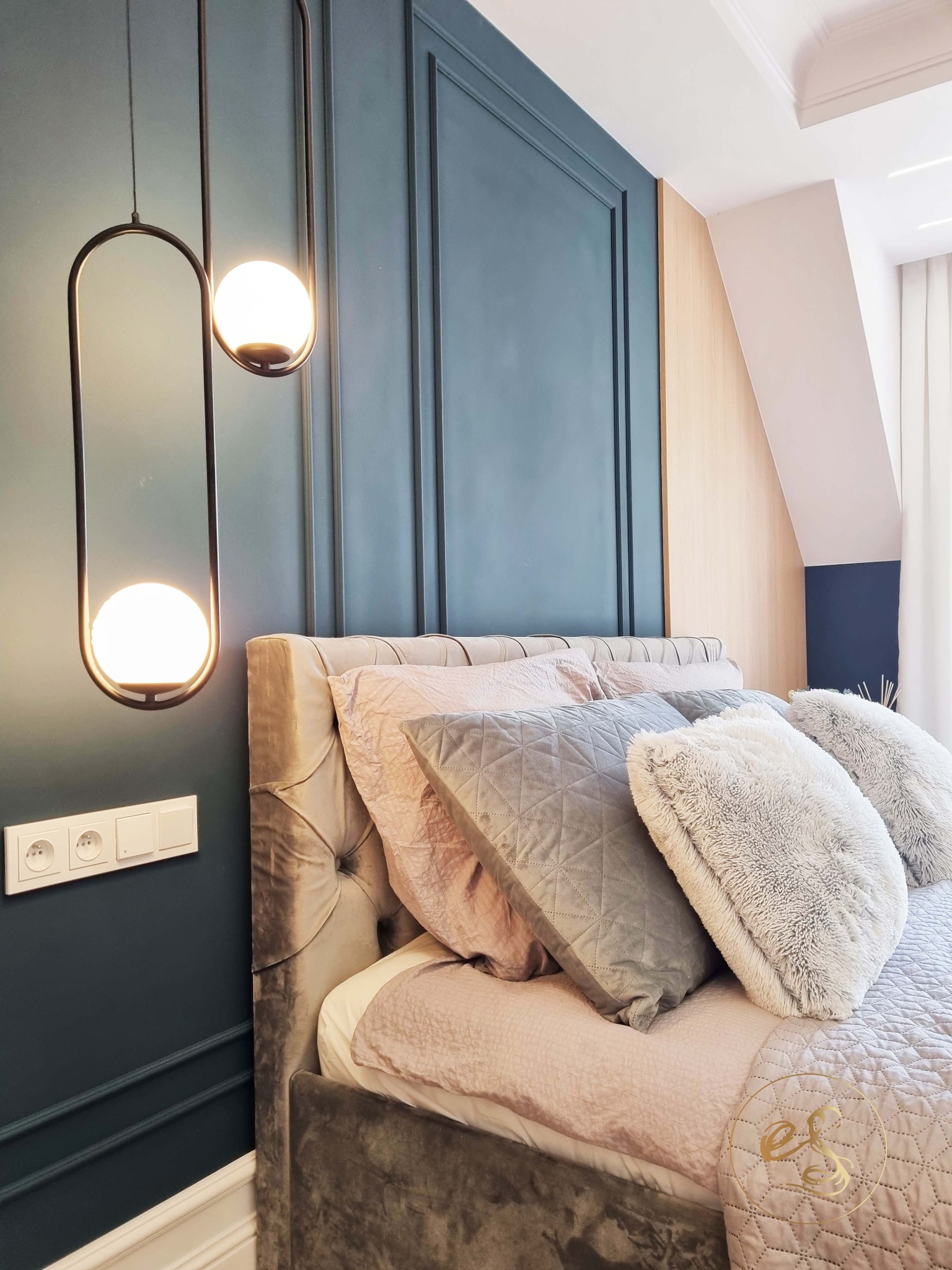 Elegancka sypialnia z ciemnozieloną ścianą z dekoracyjnymi listwami, welurowym zagłówkiem łóżka, różową pościelą, szarymi i puszystymi poduszkami oraz nowoczesnymi lampami wiszącymi z kulistymi...