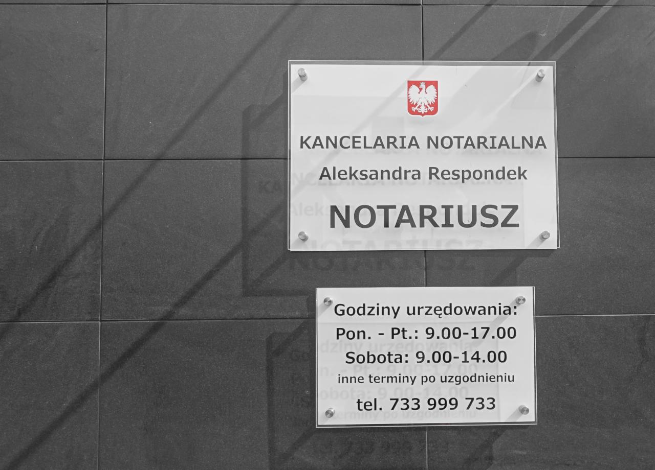 Tabliczka informacyjna na ścianie z ciemnych płytek, wskazująca na Kancelarię Notarialną Aleksandry Respondek, z godłem Polski i godzinami urzędowania.