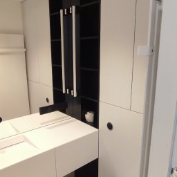 PHU PIWKO MEBLE NA WYMIAR MILENA PIWKO - Nowoczesna łazienka z białymi szafkami na wymiar z czarnymi wstawkami, wisząca umywalka z blatem i lustrem oraz toaleta.