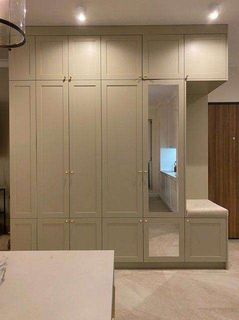 Duża, beżowa szafa wnękowa z lustrem i siedziskiem, złote uchwyty, widok na wnętrze szafy i część pomieszczenia.