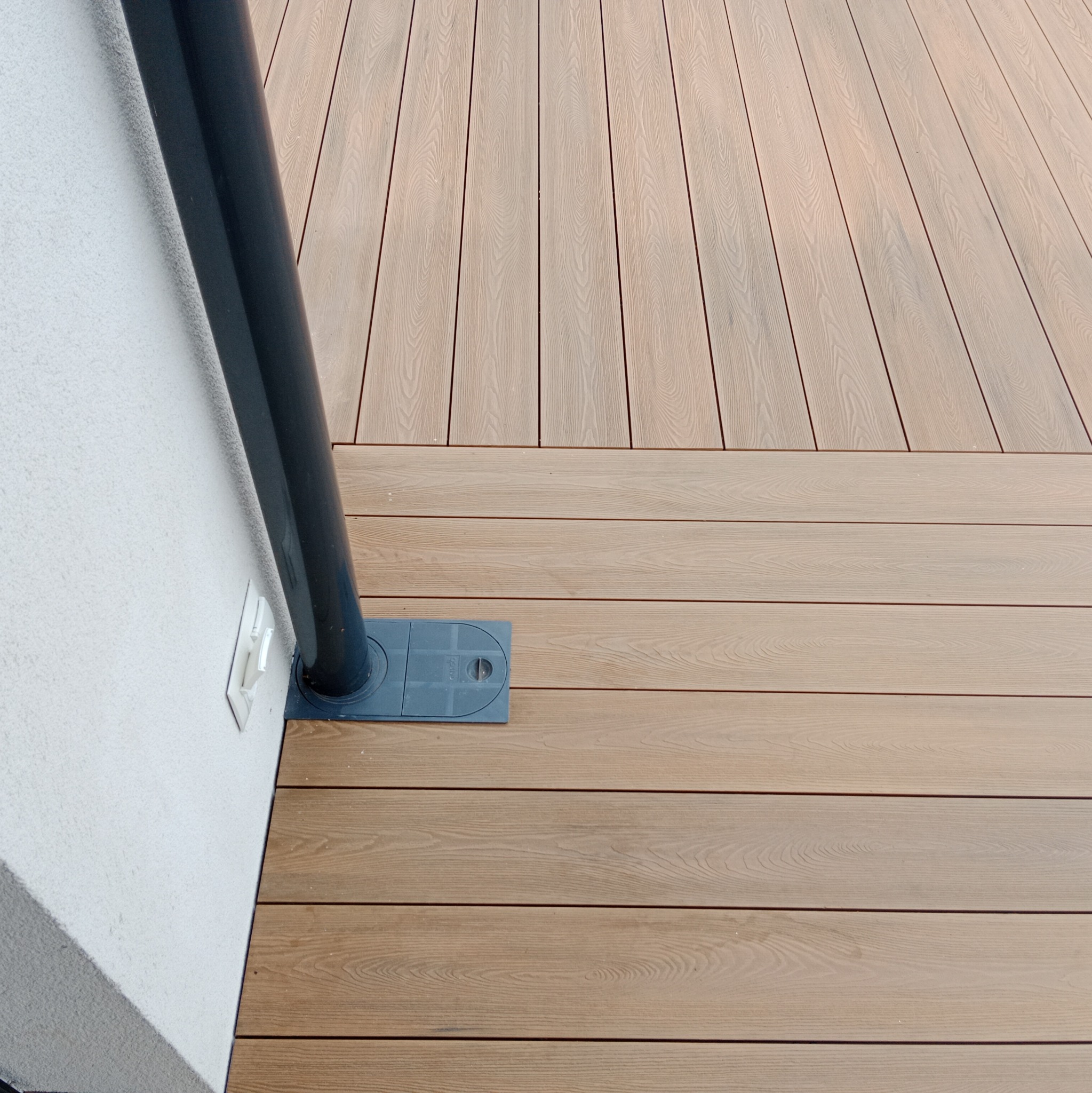 Fragment tarasu kompozytowego z odpływem przy ścianie budynku, widoczna faktura desek.