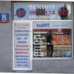 Fasada punktu serwisowego z ofertą naprawy notebooków, drukarek, kopiarek i kas fiskalnych. Na drzwiach lista autoryzowanych partnerów, w oknie neon XERO KOLOR.