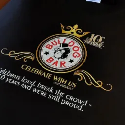 Czarna koszulka z okolicznościowym, złotym nadrukiem 'Bulldog Bar 10th Birthday' wykonanym w Bielsko-Białej.