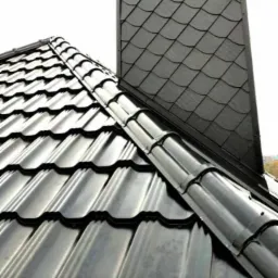 Czarny dach z metalowej dachówki modułowej, widok na komin wykończony łupkiem.