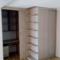 Szafa wnękowa z przesuwnymi drzwiami i biurkiem w zabudowie, z jasnego drewna, dopasowana do skosu dachu, Rychwał.