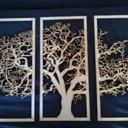 Tryptyk z wycinanymi laserowo z drewna motywami drzew na ciemnym tle, każdy element w oddzielnej ramce.
