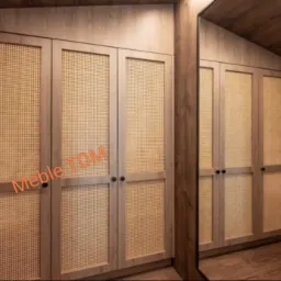 Wnętrze garderoby z szafami na wymiar, fronty z rattanową plecionką, drewniane wykończenie, widok z lustrzanego odbicia.