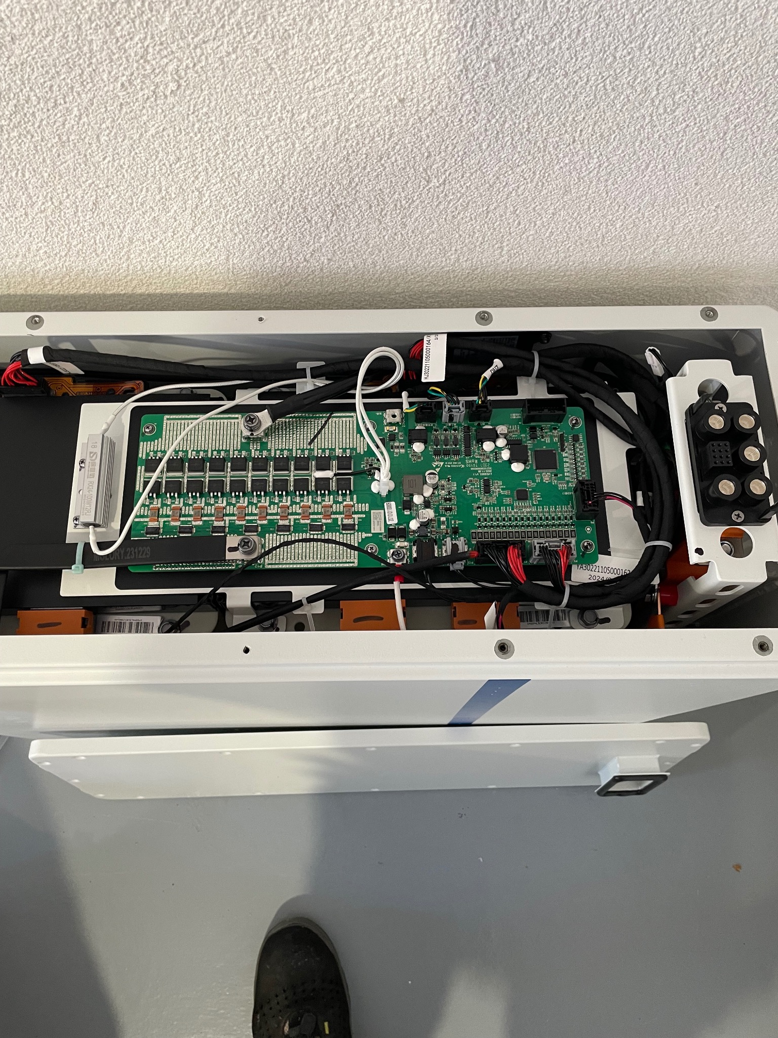 Otwarta obudowa urządzenia elektronicznego z widoczną płytą główną, kablami i elementami złącznymi. Widoczne ślady użytkowania na obudowie.