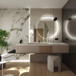 Aranżacja, projektowanie wnętrz MIA PROJEKT Maria Leśna - Nowoczesna łazienka z okrągłym lustrem podświetlanym LED, beżową szafką pod umywalką i marmurową ścianą. Minimalistyczny design z rośliną w rogu.