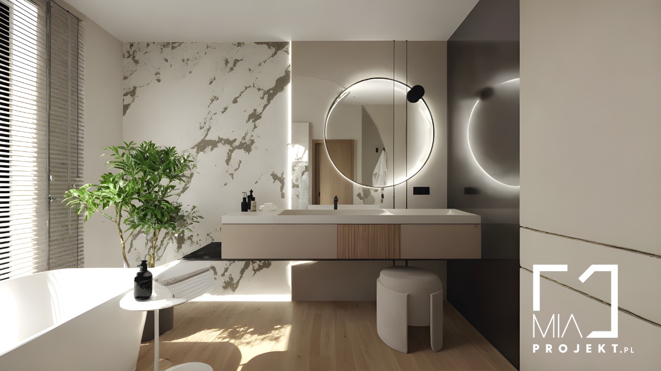 Nowoczesna łazienka z okrągłym lustrem podświetlanym LED, beżową szafką pod umywalką i marmurową ścianą. Minimalistyczny design z rośliną w rogu.