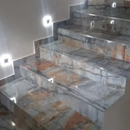 Wykończone schody z płytek imitujących marmur, oświetlone kwadratowymi lampami ściennymi, z widocznymi detalami wykończenia krawędzi.