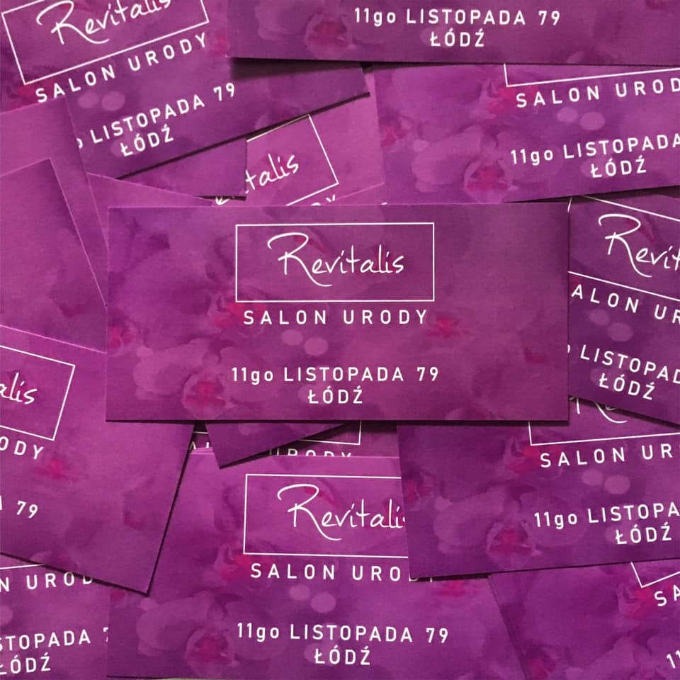 Stos wizytówek salonu urody Revitalis z Łodzi, na fioletowym tle z motywem kwiatowym, adres 11 Listopada 79.