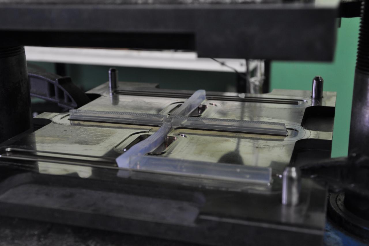 Forma wtryskowa z tworzywa sztucznego w prasie, widoczne elementy mocujące i kanały doprowadzające materiał.