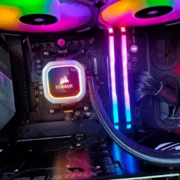 Wnętrze komputera stacjonarnego z podświetleniem RGB na wentylatorach, pamięci RAM i chłodzeniu procesora Corsair, widoczna płyta główna Asus Strix.