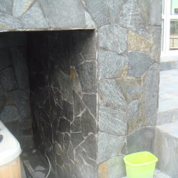 PHU SZAFIR - Kamienna elewacja zewnętrzna z wnęką, obok schody i wiadro, widoczna wanna w folii.