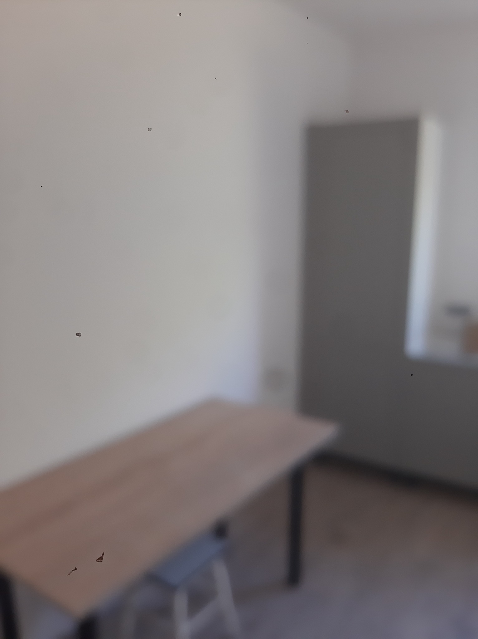 Przygotowane do malowania wnętrze: stół, krzesło i szafa przy ścianie. Widoczne niedoskonałości ściany przed malowaniem.