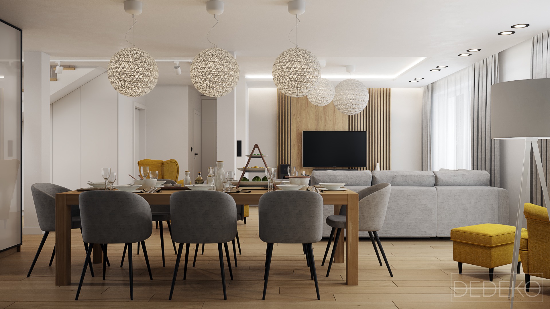 Jasne wnętrze jadalni z drewnianym stołem, szarymi krzesłami, dekoracyjnymi lampami wiszącymi i żółtymi akcentami kolorystycznymi w postaci foteli i podnóżka, z salonem w tle.