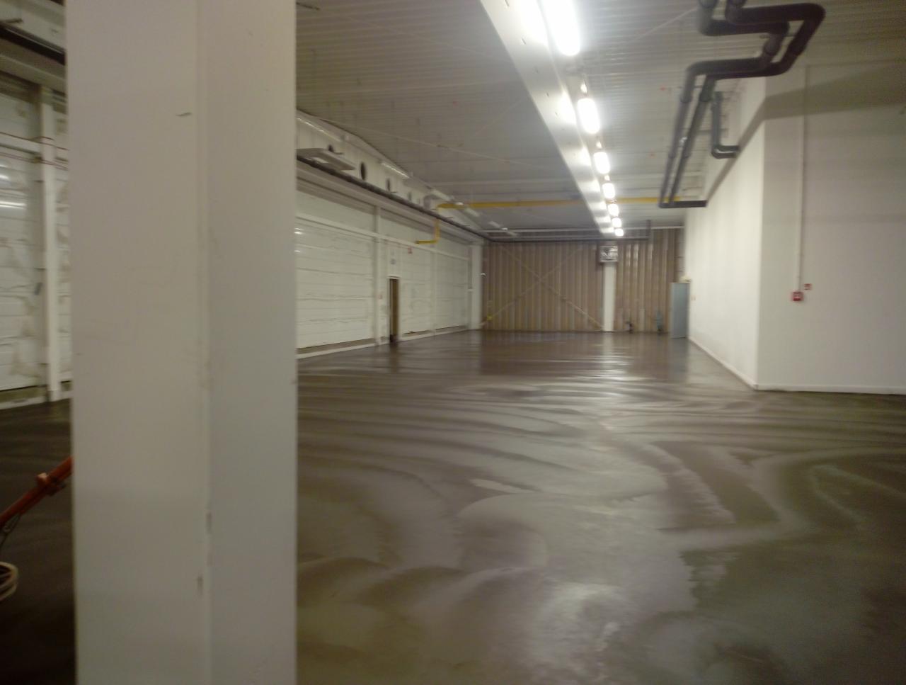 Świeżo wylana posadzka w hali przemysłowej w Słowikowie, widoczne ślady po rozprowadzaniu masy.