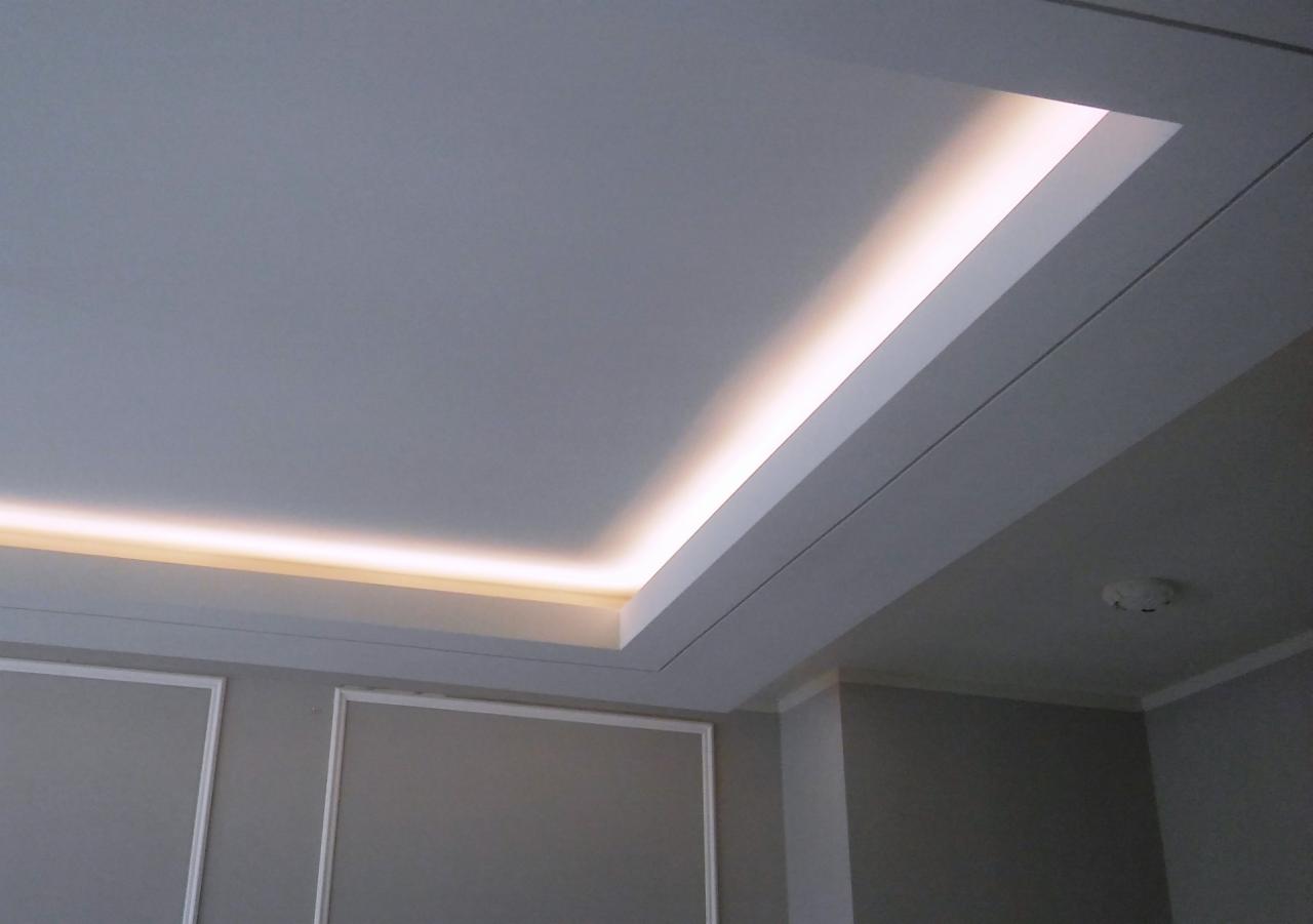 Nowoczesne oświetlenie sufitowe z listwą LED wpuszczoną w podwieszany sufit, widoczny czujnik dymu.