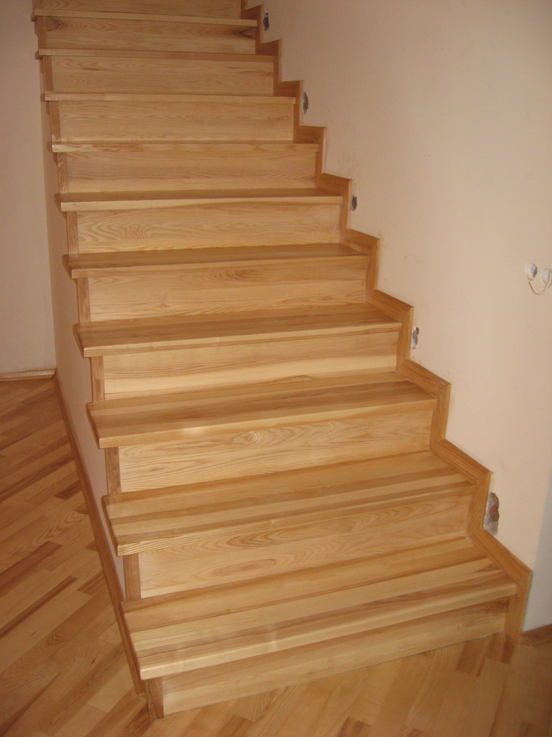 Jasne, drewniane schody bez poręczy w trakcie montażu, widoczne niedoskonałości wykończenia ścian i podłogi.