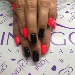 Bellezza Salon Fryzjersko-Kosmetyczny - Dłonie z pomalowanymi paznokciami w kolorze neonowej czerwieni i czerni na tle z logo Indigo.
