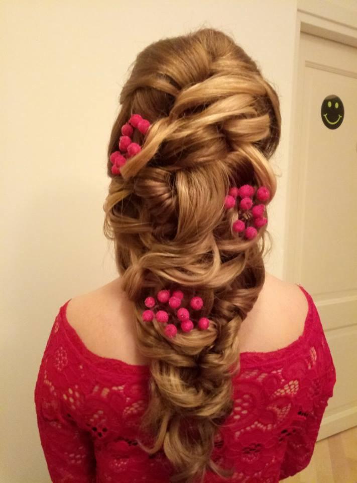 Upięcie blond włosów z wplecionymi czerwonymi ozdobami w kształcie kulek, widok z tyłu, kobieta w czerwonej koronkowej bluzce.