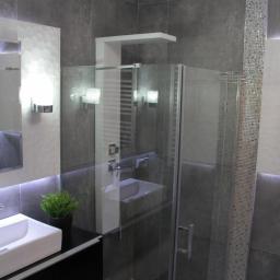 BudEkspert - Nowoczesna łazienka z szarymi płytkami, szklaną kabiną prysznicową, umywalką nablatową, dekoracyjnym oświetleniem LED i kryształowym żyrandolem.