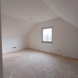 Usługi remontowo - budowlane Zbigniew Rzepka - Poddasze z oknem dachowym po wykonaniu gładzi, widoczne przygotowane podłoże pod posadzkę, wystające kable elektryczne i puszka instalacyjna.