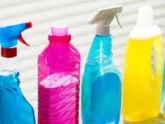 Różnokolorowe butelki z płynami do czyszczenia z rozpylaczami i dozownikami, ustawione obok siebie na jasnym tle.