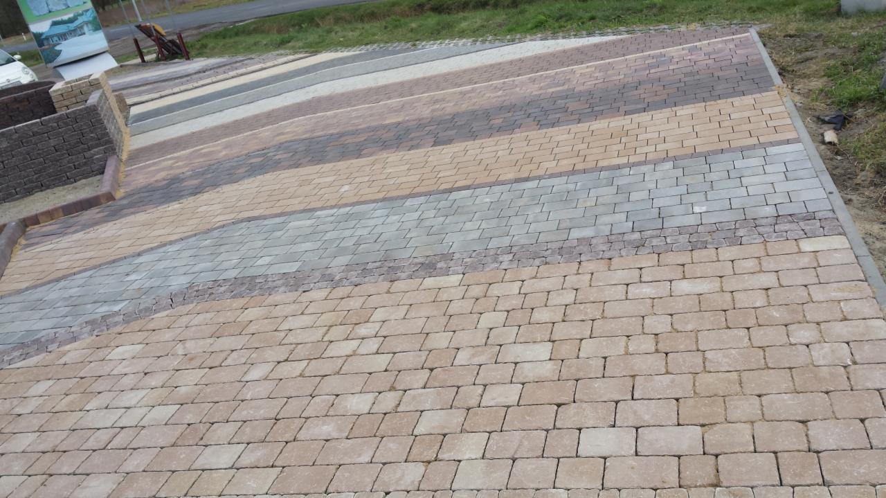 Ekspozycja wzorów kostki brukowej w Wołominie. Różne kolory i faktury ułożone w pasy, prezentacja możliwości aranżacyjnych.