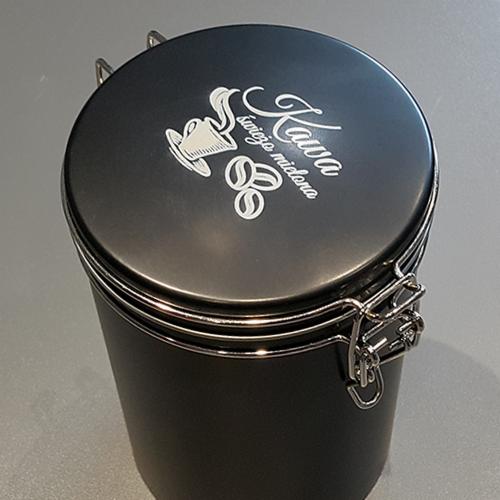 Czarny metalowy pojemnik na kawę z srebrnym nadrukiem 'Kawa świeżo mielona' i rysunkiem filiżanki oraz ziaren kawy, zamknięty na metalowe zatrzaski.