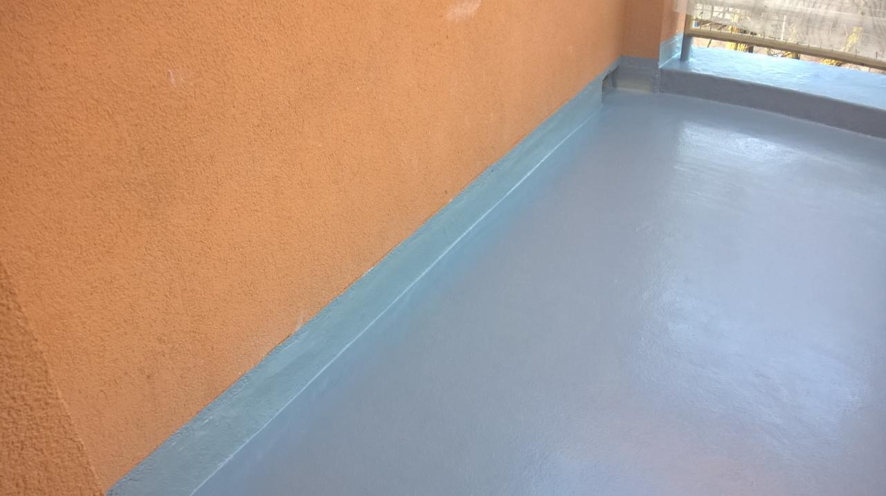 Balkon po nałożeniu jasnoszarej, wodoodpornej powłoki z niebieskimi detalami przy ścianie i krawędziach.