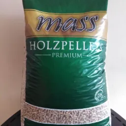 Worek z drewnianym granulatem opałowym, widoczny napis 'HOLZPELLET PREMIUM' i logo 'mass', umieszczony na czarnym, metalowym podłożu.