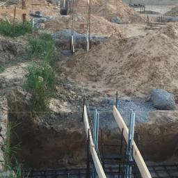 DNV Realiz LTD Sp. Z o.o. S.k - Wrocław: Etap budowy fundamentów z widocznymi prętami zbrojeniowymi, szalunkiem i instalacją uziemiającą w wykopie.