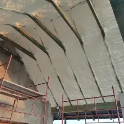 Poddasze ocieplone pianką, widoczne krokwie i rusztowanie, światło słoneczne podkreśla strukturę pianki.