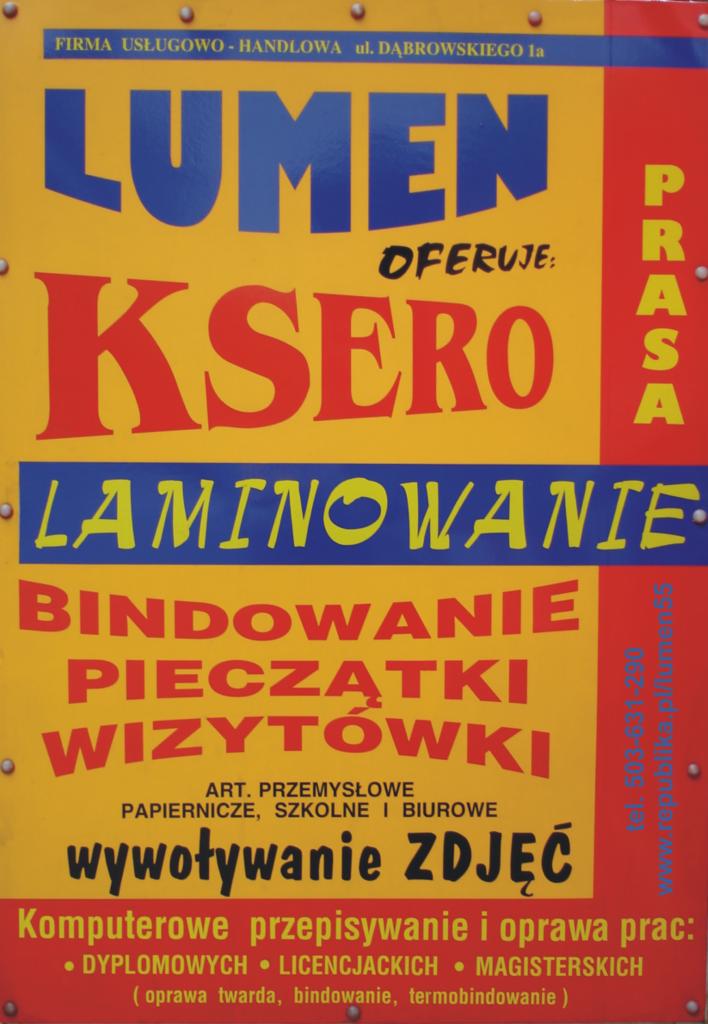 Tablica reklamowa firmy Lumen oferującej ksero, prasę, laminowanie, bindowanie, pieczątki, wizytówki, artykuły papiernicze i wywoływanie zdjęć, z adresem i numerem telefonu.