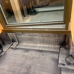 Usługi Blacharsko-Dekarskie - Szczegółowe ujęcie uszczelnienia dachu wokół okna dachowego z widoczną izolacją i elementami konstrukcyjnymi. Precyzyjne wykończenie detali dekarskich.