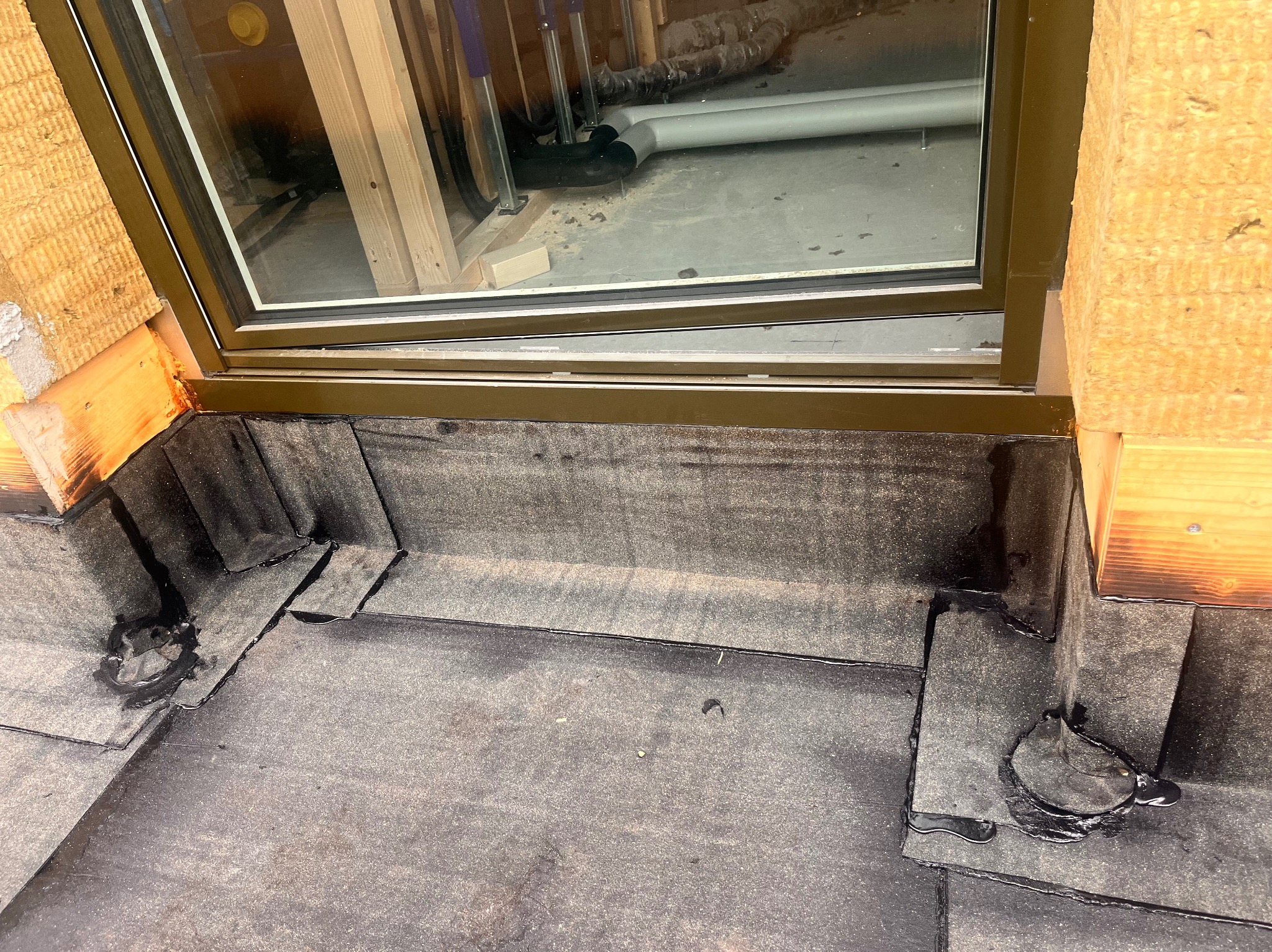 Szczegółowe ujęcie uszczelnienia dachu wokół okna dachowego z widoczną izolacją i elementami konstrukcyjnymi. Precyzyjne wykończenie detali dekarskich.