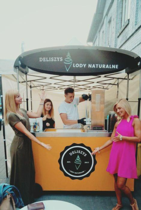 Mobilny punkt sprzedaży lodów naturalnych Deliszys z obsługą i klientkami, widoczne logo i nazwa firmy.