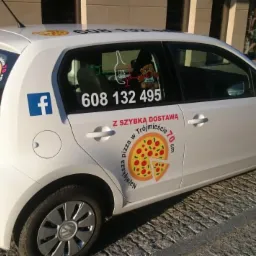 Biały samochód dostawczy z reklamą pizzerii: naklejki z logo, numerem telefonu i informacją o szybkiej dostawie pizzy w Trójmieście, widoczne również naklejki z logo Facebooka.