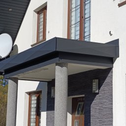 Firma TIMBER Artur Terpiłowski - Nowoczesne zadaszenie nad wejściem do domu z białymi ścianami, kamienną elewacją i kolumnami o fakturze lastryko, widoczna antena satelitarna.