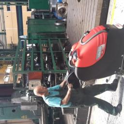 Centro-Tech Karol Dybowski - Operator w kombinezonie obsługuje automat szorująco-zbierający Ruby 55b na betonowej posadzce hali produkcyjnej, w tle widoczna suwnica i maszyny przemysłowe.