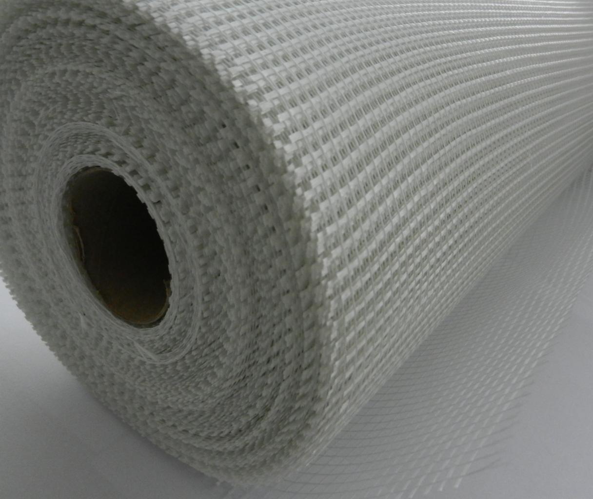 Rolka białej siatki z włókna szklanego do wzmacniania tynków, widoczna struktura oczek i tekturowa tuba wewnątrz.