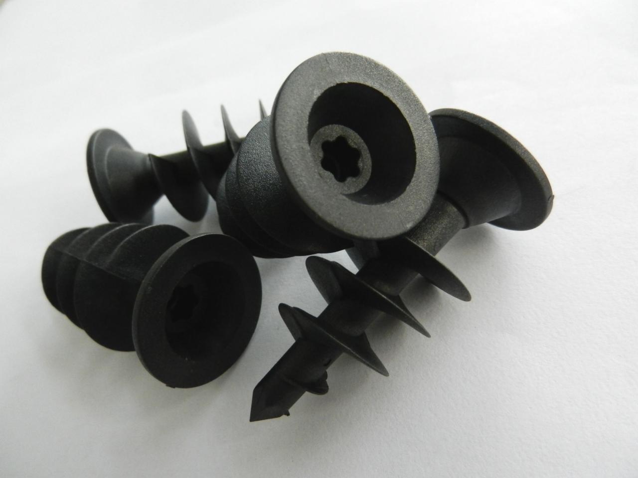 Czarne, plastikowe kołki rozporowe z wkrętem, widoczne na białym tle, z wyraźnymi spiralnymi skrzydełkami.