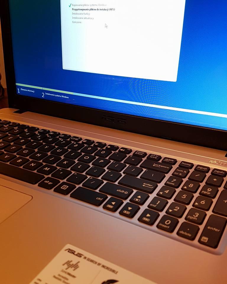Laptop ASUS podczas instalacji systemu Windows, widoczny ekran z postępem instalacji na 48% oraz klawiatura i naklejka z logo ASUS.
