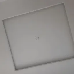 Kwadratowy sufit podwieszany z delikatnym wgłębieniem, pomalowany na biało, widok z dołu pod kątem.