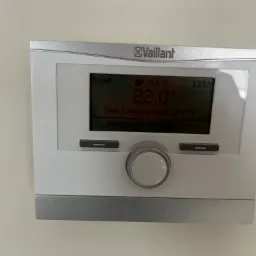 Panel sterowania ogrzewaniem Vaillant zamontowany na ścianie, wyświetlający temperaturę 22 stopnie Celsjusza i ustawioną temperaturę grzania na 22 stopnie Celsjusza, godzina 13:13, temperatura...