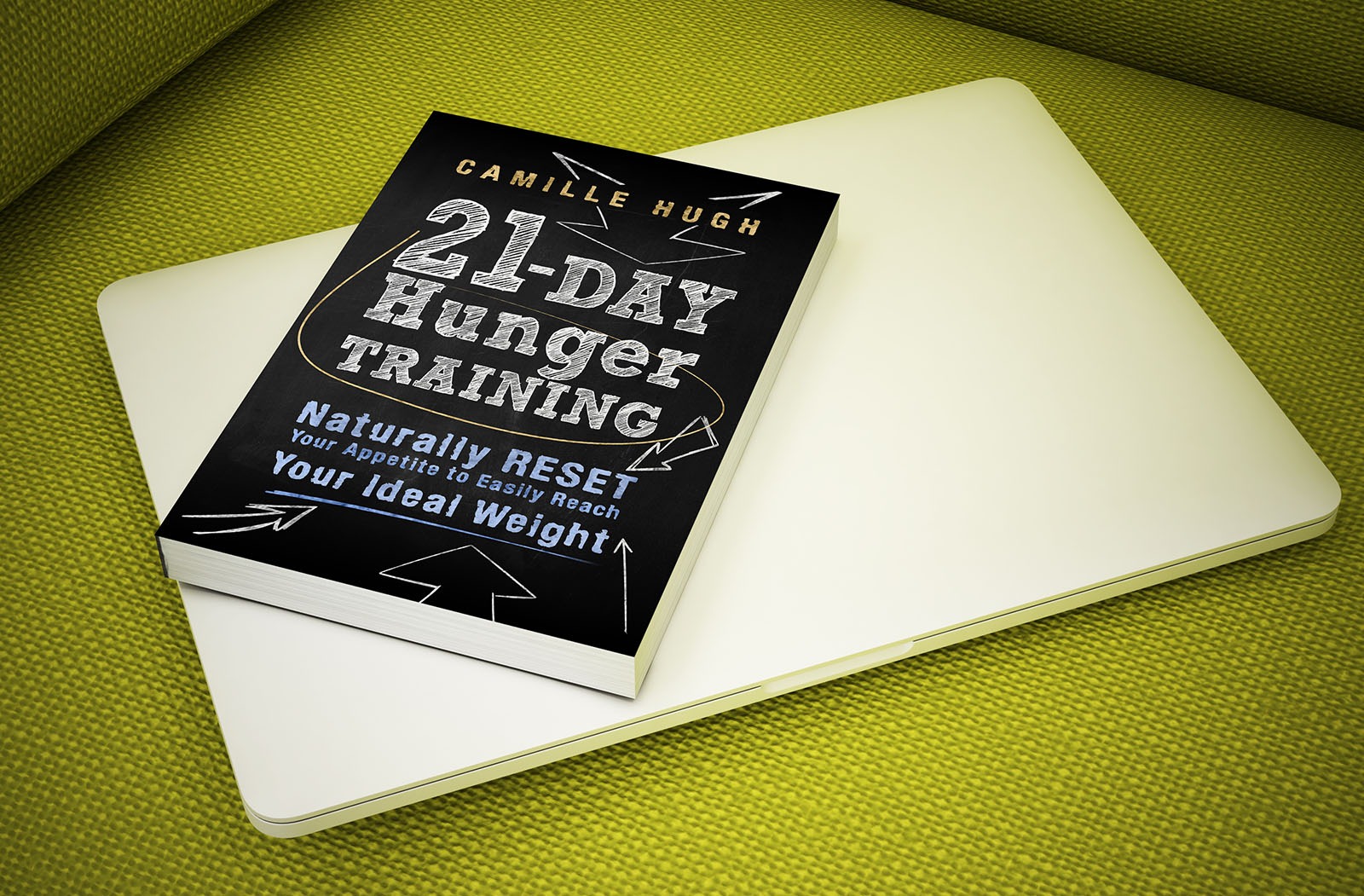 Książka '21-Day Hunger Training' autorstwa Camille Hugh leżąca na białym laptopie na zielonym tle.